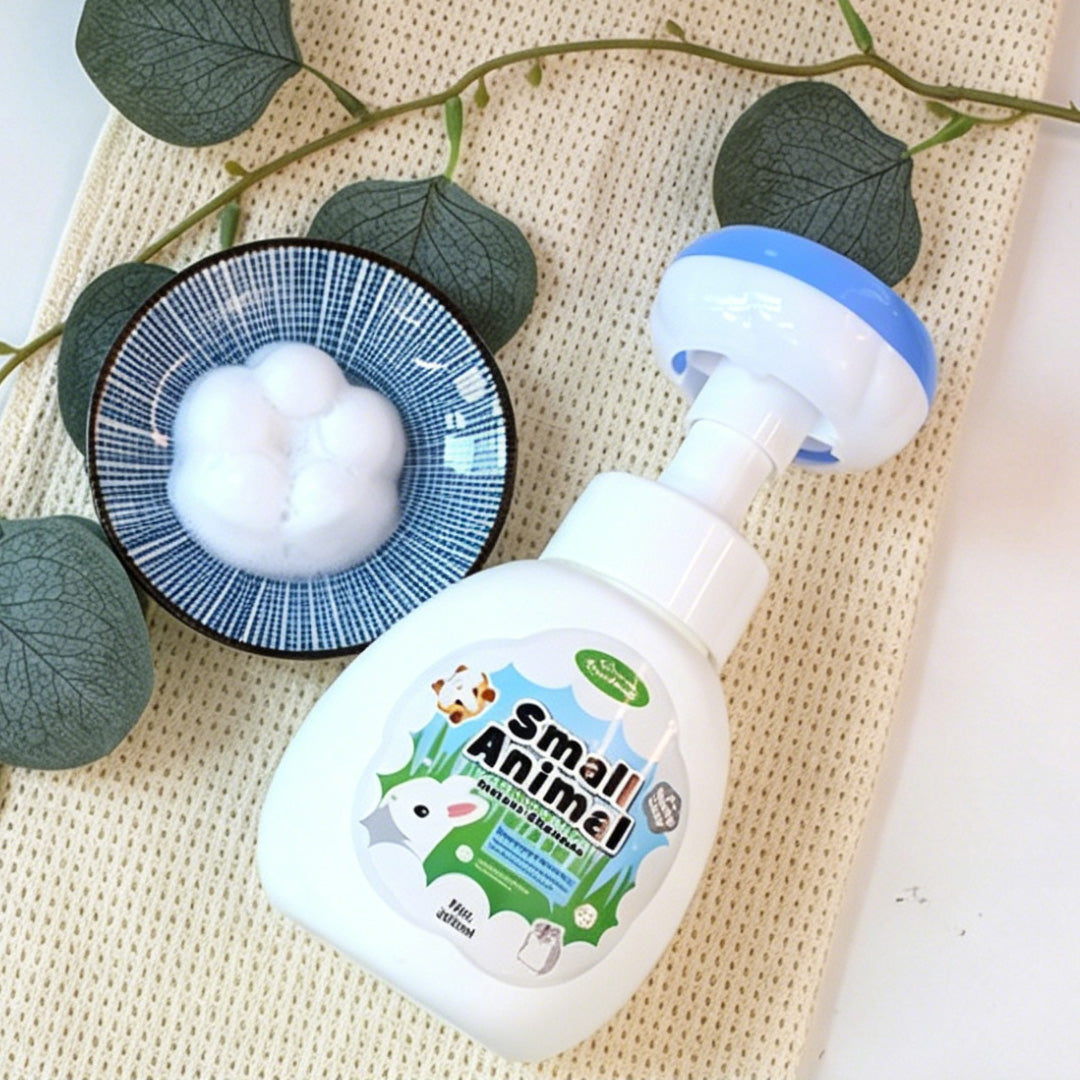 A flat-lay Small Animal no-rinse foaming shampoo bottle, paired with a bowl of fluffy foam, highlighting its soft, foamy texture.
